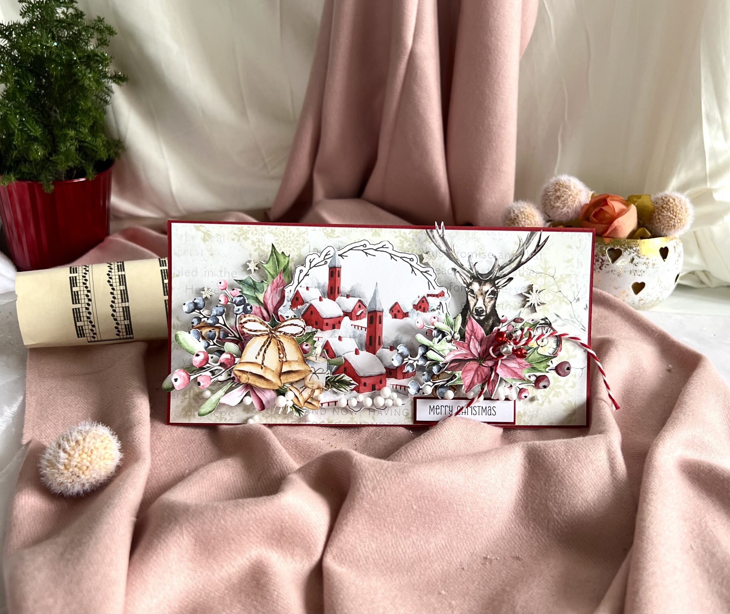 Artistic Christmas card with reindeer and winter village displayed in a decorative box